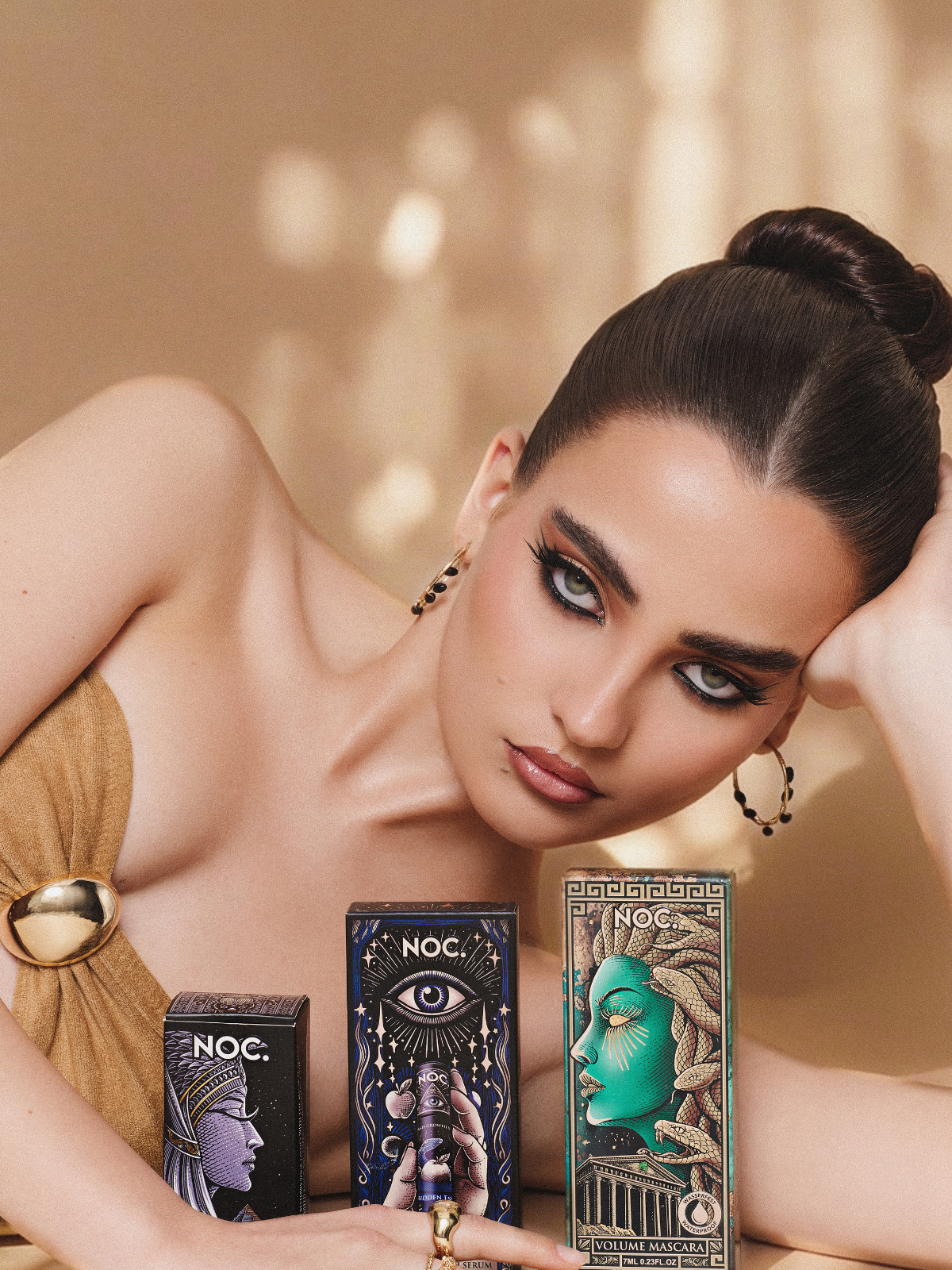 Model mit voluminösen Wimpern neben NOC. Cosmetics Wimpernzange Cleopatra's Spell, Wimpernserum Forbidden Essence und Volumen Mascara wasserfest
