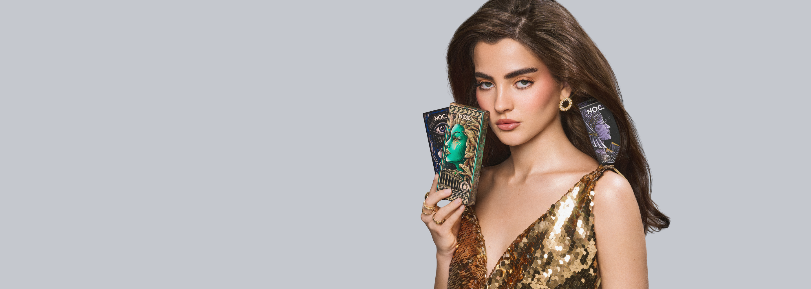 Model hält NOC. Cosmetics Wimpernserum Forbidden Essence, Volumen Mascara wasserfest und Wimpernzange Cleopatra's Spell